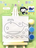 Children's drawing set with whale design, paint pots, and an easel on a green background.
