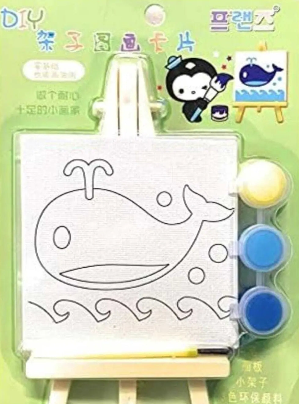 Children's drawing set with whale design, paint pots, and an easel on a green background.